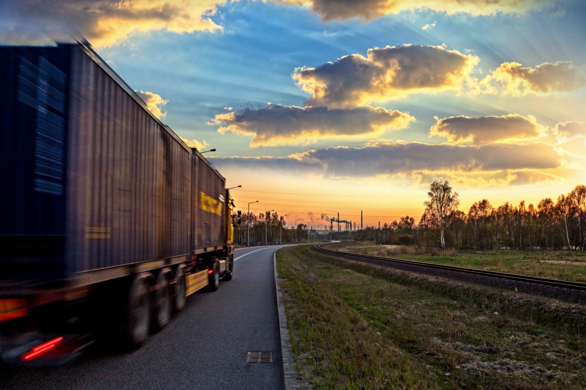 A truck driving down the road near some grass.